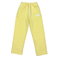 Yellow sweatpants with a white drawstring and a small white oval logo on the left thigh, shown against a plain white background.
